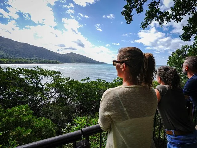 Group of tourists standing at a lookout point viewing the ocean and mountains.