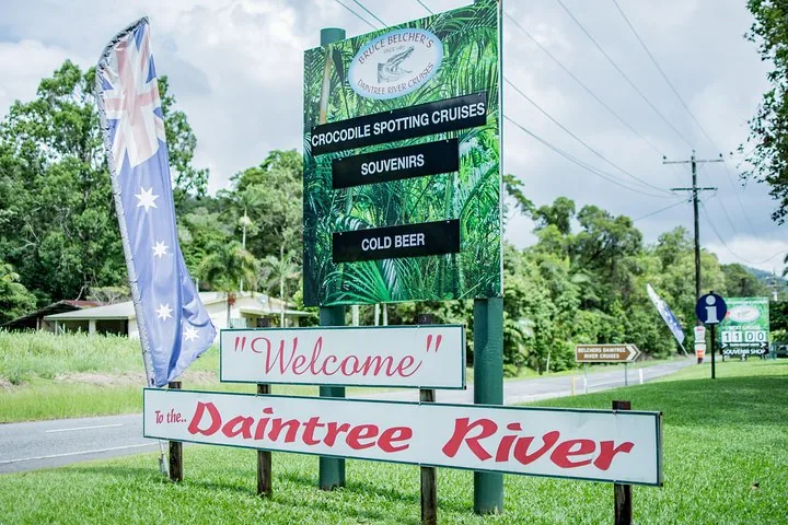A roadside sign advertising Bruce Belcher's Daintree River Cruises with an Australian flag.